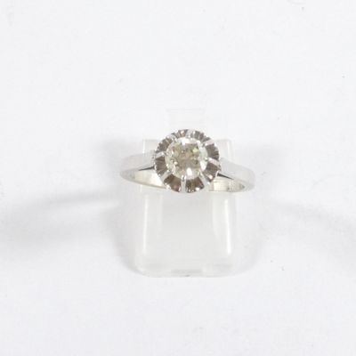 un gros plan d'une bague sertie d'un diamant, posée sur une surface blanche