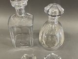 three glass bottles and a small crystal bowl on a table