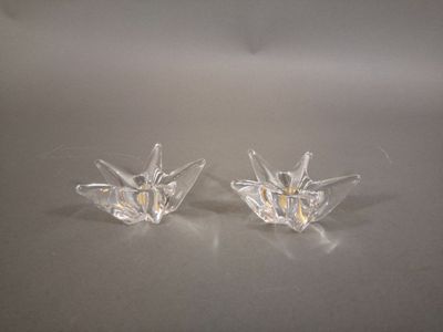 une paire de bougeoirs en verre transparent posés sur une surface blanche