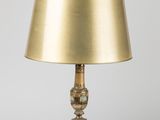 a brass table lamp with a gold shade on a white background