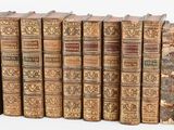 several old books are lined up in a row on a white surface