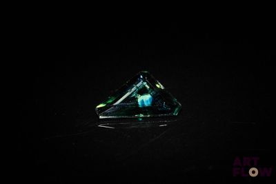 a close up of a triangular shaped glass object on a black surface