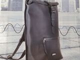 the back of a brown backpack with a black strap