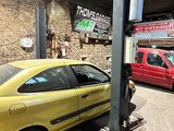 une voiture jaune garée dans un garage à côté d'une voiture rouge