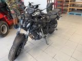 a black motorcycle parked in a garage with a man standing next to it