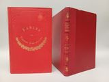 two red books sitting next to each other on a white surface