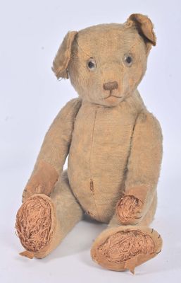 un ours en peluche marron assis par terre