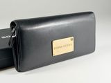 the black leather wallet is open and has a gold plate on it