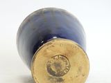 a close up of a blue vase on a white surface