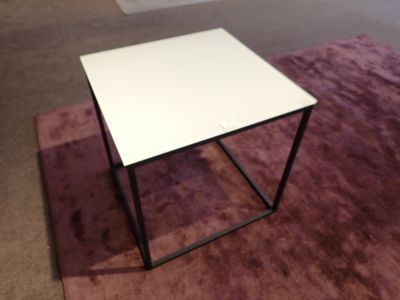 une petite table au plateau blanc posée sur un tapis violet