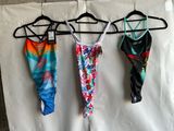three women ' s swimsuits hanging on a hanger on a wall