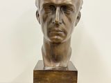 bronze bust of a man on a wooden base on a table