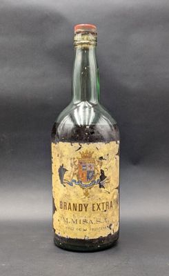 Une vieille bouteille de « Brandy Extra » est posée sur une table