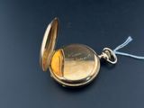 a gold pocket watch with a chain on a black surface