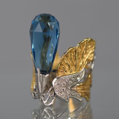 une image représentant une bague sertie d'une topaze bleue et ornée d'une feuille d'or