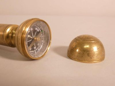 une horloge dorée et une cloche en laiton posées sur un fond blanc