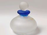 a glass bottle with a blue top sitting on a white surface