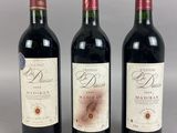 three bottles of red wine are lined up on a table