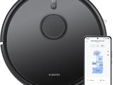 a black robot vacuum cleaner with a phone next to it