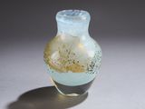 un petit vase en verre posé sur une surface blanche