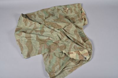 une chemise camouflage posée sur une surface blanche, sur fond blanc