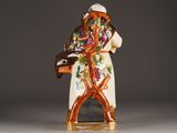 a figurine of a man with a hat and a bag