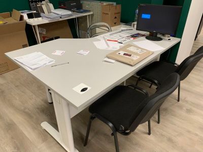 une table blanche sur laquelle se trouve un ordinateur, dans une pièce
