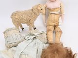 a doll and a sheep on the ground next to a pile of clothes