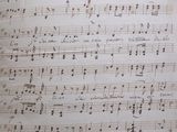 an old sheet of music sitting on top of a wooden table