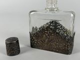a small glass bottle with a metal stopper next to it
