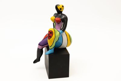 figurine représentant une femme assise sur un bloc noir
