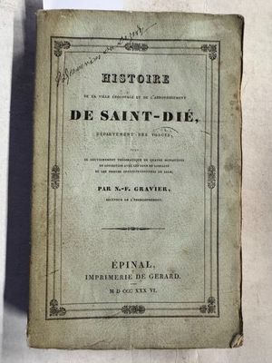 un vieux livre posé sur une table à côté d'un mur blanc