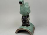 statue of a bird sitting on top of a book on a white surface