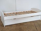 a white bed with wooden slats in a room