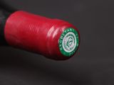 a close up of a red wine bottle with a green cap