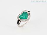 a heart shaped emerald and diamond ring on a white background