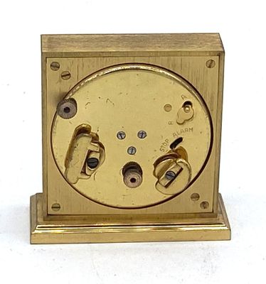 une horloge en or posée sur une surface blanche