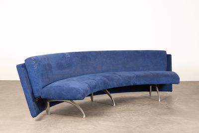 un canapé bleu aux lignes courbes, avec des pieds chromés, dans une pièce
