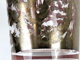 a glass vase with a gold and red design on it