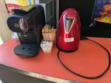 une cafetière rouge posée sur un plan de travail, à côté d'une tasse de café