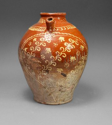 a brown vase with designs on it on a gray surface