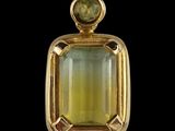 a close up of a pendant with a green stone on it