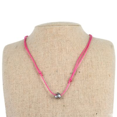 un collier en cordon rose orné d'une perle argentée, porté par un mannequin