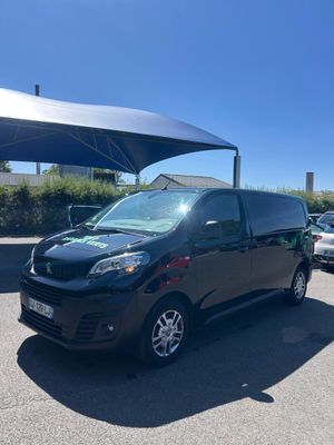 une camionnette noire garée sur un parking, à l'abri d'un parasol