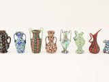 several different colored vases are lined up on a white surface