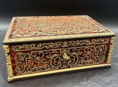 une boîte rouge et dorée posée sur une surface noire