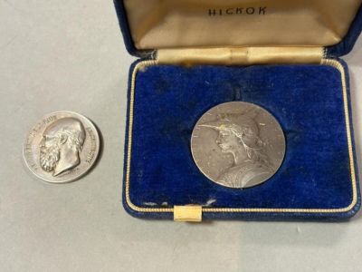 une pièce d'argent dans un étui bleu, à côté d'une pièce d'argent