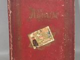 an old book with a red cover sitting on top of a table