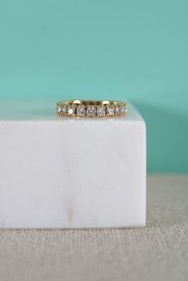 un gros plan d'une bague en or jaune posée sur un bloc de marbre blanc
