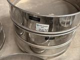 three metal pans sitting on a counter with a metal strainer